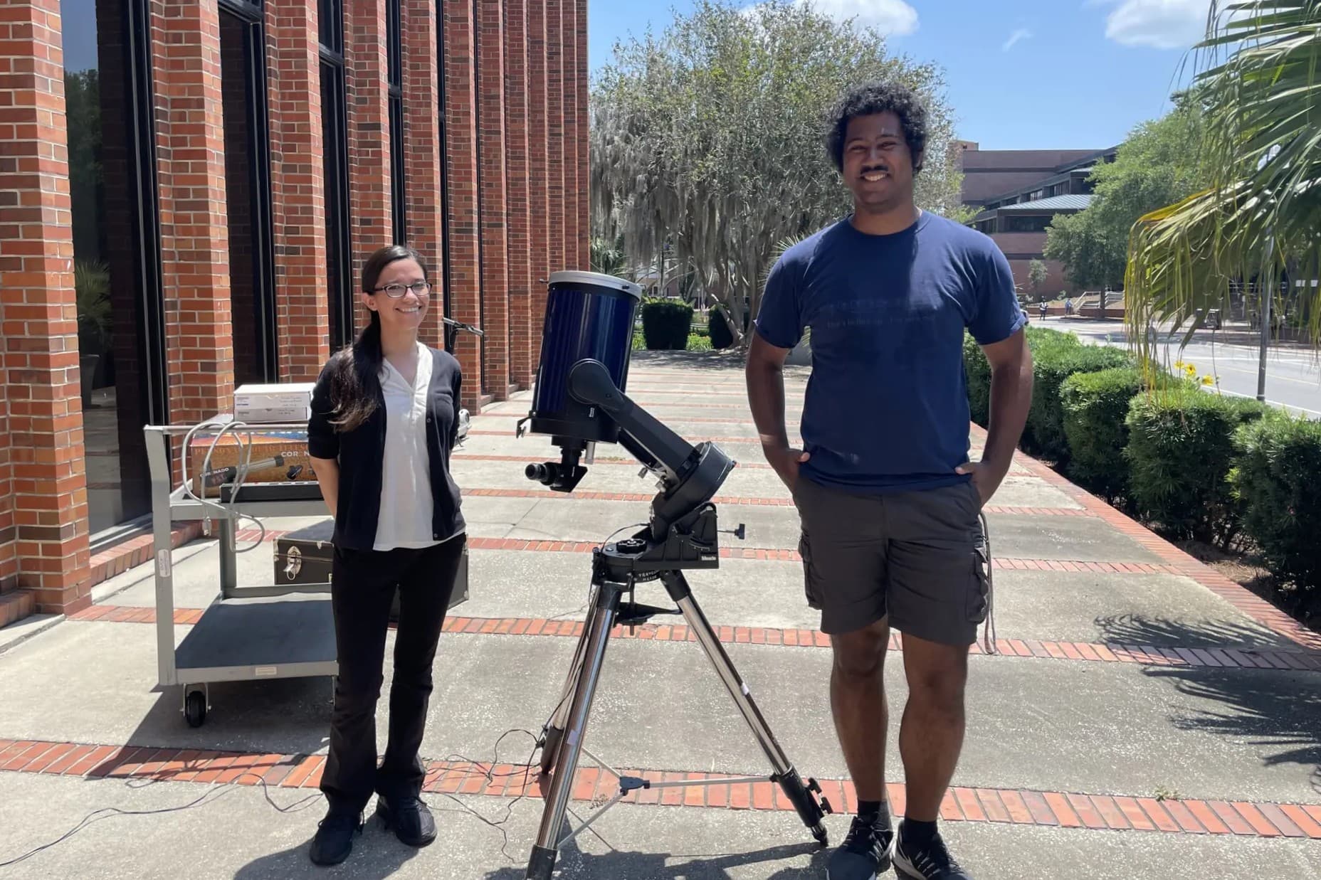 Woman and man standing next to a telescope